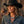 Load image into Gallery viewer, A woman wearing a black cowboy hat and a blue denim shirt, styled with a western silver necklace, set against a rustic wooden background.
