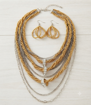 A gold and silver beaded necklace set with matching teardrop earrings, displayed on a light wood background.