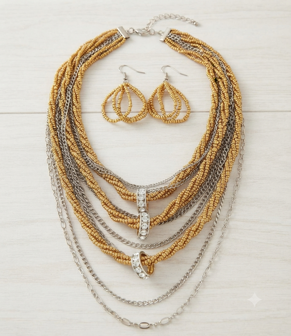 A gold and silver beaded necklace set with matching teardrop earrings, displayed on a light wood background.