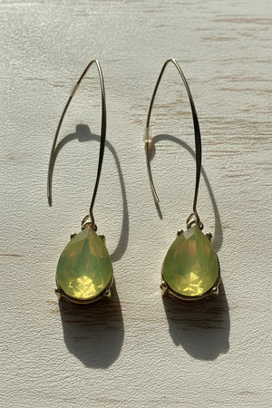 Teardrop-shaped green earrings on a light gray background