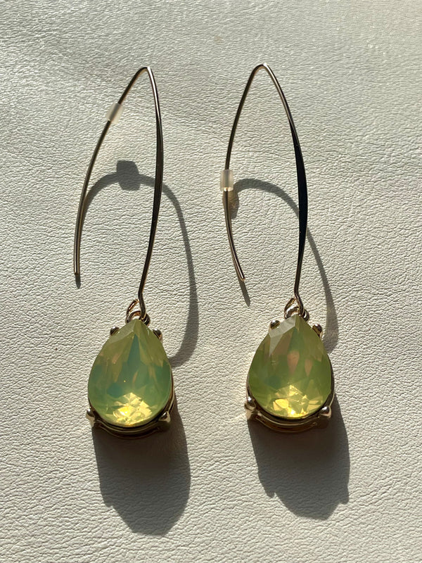 Teardrop-shaped green earrings on a light gray background