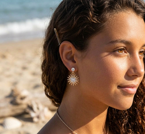 Woman wearing sun-shaped earrings on a beach