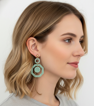 Woman wearing a pair of green earrings against a white background