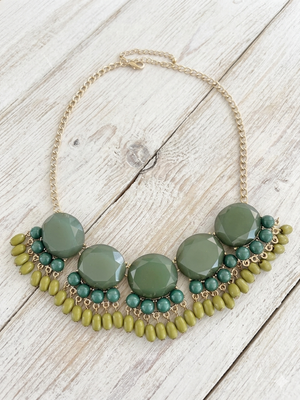 Necklace with green and gold beads on a wooden surface