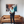 Load image into Gallery viewer, Woman standing in a living room with a brown leather sofa and abstract art on the wall.
