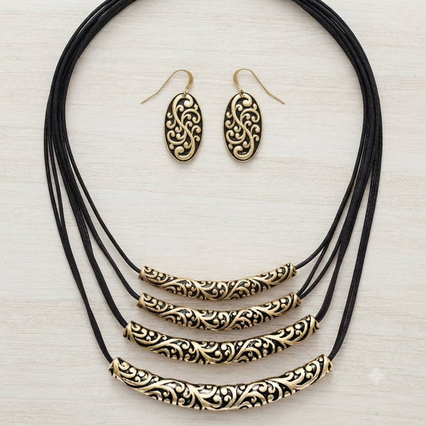 A jewelry set featuring a multi-strand black cord necklace with ornate gold filigree bar beads and matching oval drop earrings, displayed on a light wood background.