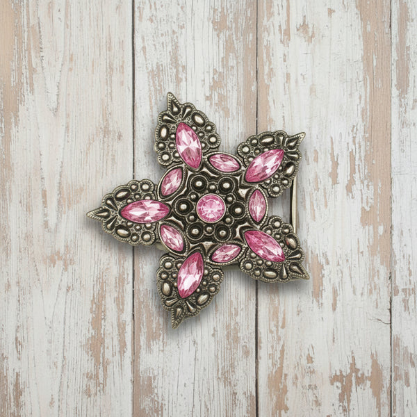 A vintage-style star-shaped brooch featuring an antiqued silver-tone filigree frame and multiple pink marquise and round crystals, shown on a plain white background.