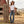 Load image into Gallery viewer, A woman stands outdoors at a rustic barn wearing a white crew-neck t-shirt, blue jeans with a western belt, and a brown cowboy hat.
