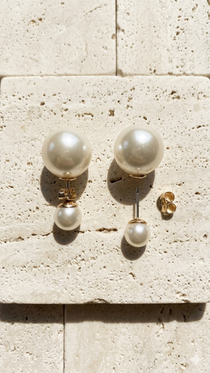 Pair of pearl earrings on a textured stone surface