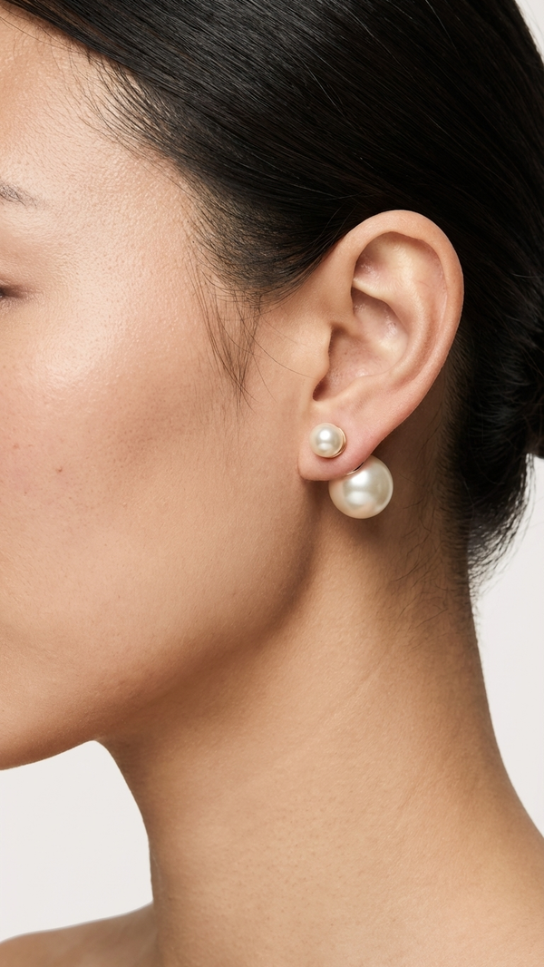 Close-up of a person wearing pearl earrings with a neutral background