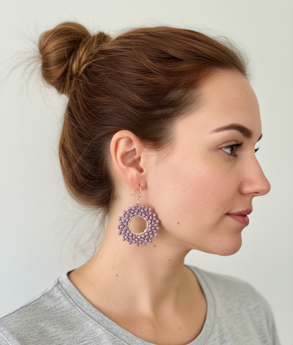 Woman wearing a pair of purple earrings against a plain background