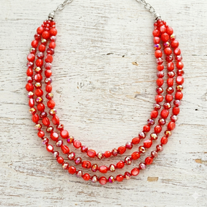 Red beaded necklace on a light wooden surface