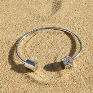 Silver bracelet with square charms on a sandy surface