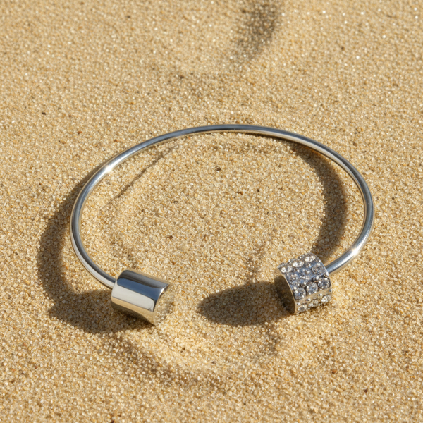 Silver bracelet with square charms on a sandy surface