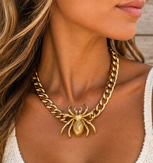 Gold spider necklace worn on a tanned model