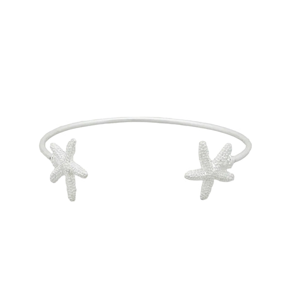 Silver star-shaped earrings on a clear stand against a light gray background