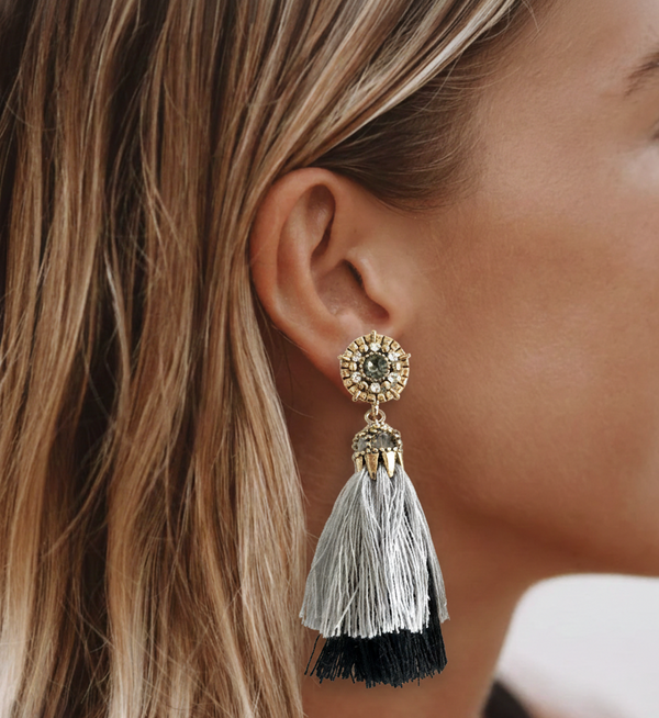 Close-up of a woman's ear wearing a decorative earring with tassels.