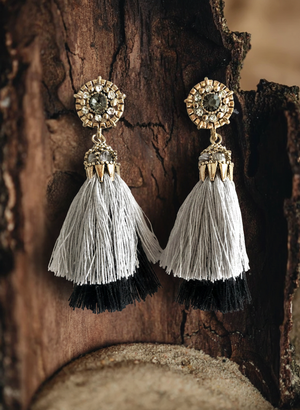 Pair of tassel earrings with gold tops on a wooden background