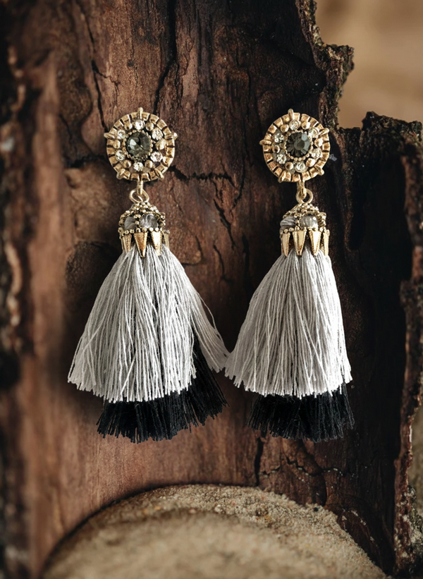 Pair of tassel earrings with gold tops on a wooden background