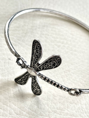 Silver dragonfly-shaped bracelet on a white background