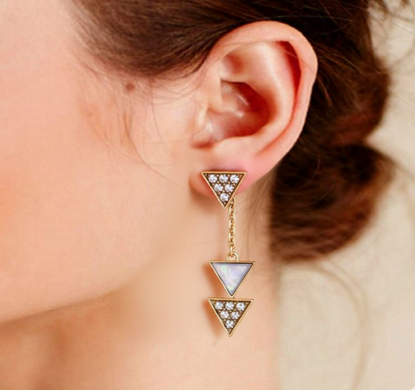 Triangle-shaped earrings with gemstones worn by a person