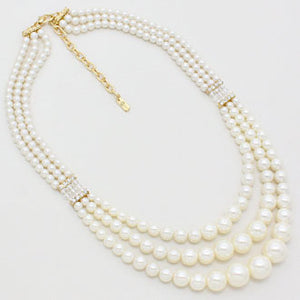 Cream three strand faux pearl necklace on white background original photo