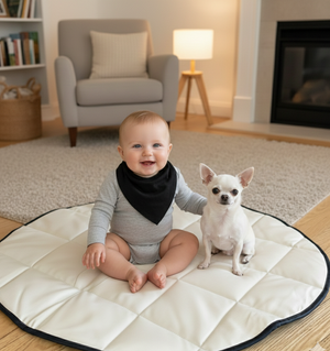 Baby and small dog sitting on a round quilt in a cozy living room.