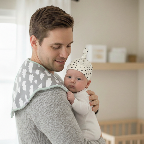 Man holding a baby in a nursery setting with a crib in the background