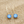 Load image into Gallery viewer, Gold earrings with blue gemstones on a wooden surface
