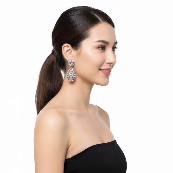Woman wearing a black strapless dress and large pearl earrings on a white background