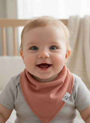 Baby wearing a pink bib with a neutral background