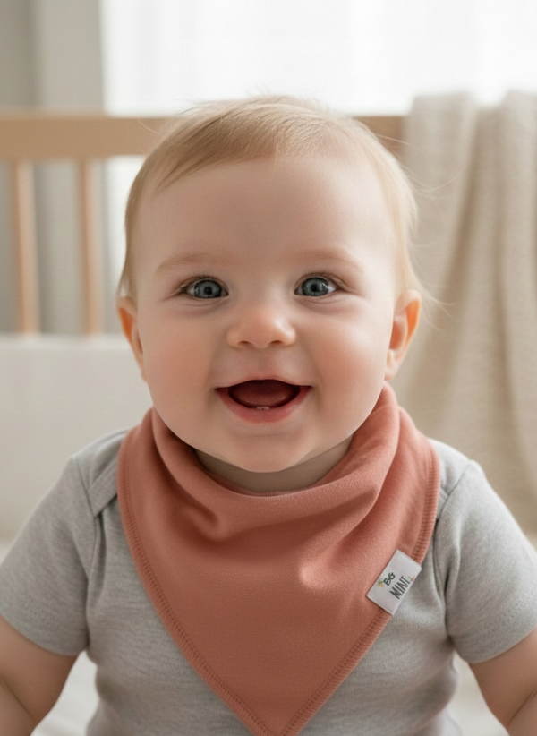 Baby wearing a pink bib with a neutral background