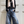 Load image into Gallery viewer, Person wearing a black sweater, blue jeans, and a pink scarf against a white paneled wall.

