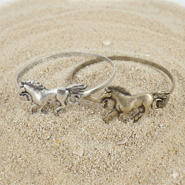 Silver bracelet with horse charms on a sandy background