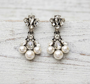 Pair of pearl and crystal earrings on a light wooden surface