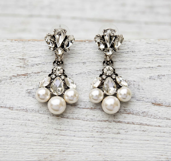 Pair of pearl and crystal earrings on a light wooden surface