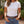 Load image into Gallery viewer, A woman wearing a plain white short-sleeve crewneck t-shirt tucked into blue jeans with a brown leather belt featuring a large silver buckle, set against a blurred outdoor garden background.
