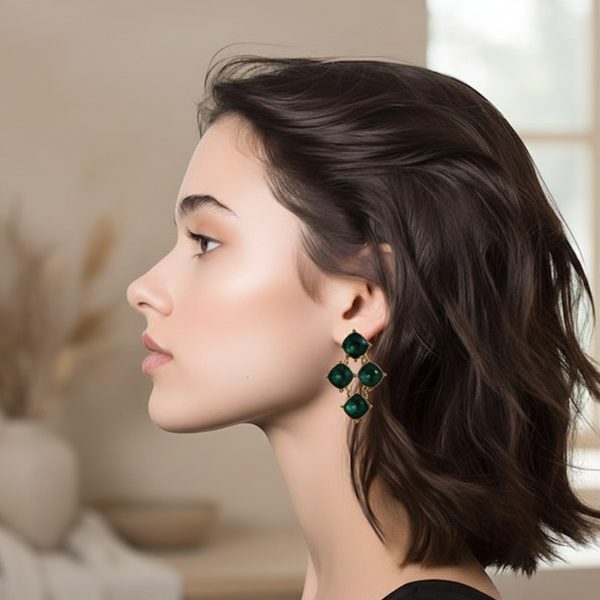 Woman wearing green earrings in a blurred indoor setting