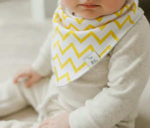 Baby wearing a yellow and white zigzag patterned bib
