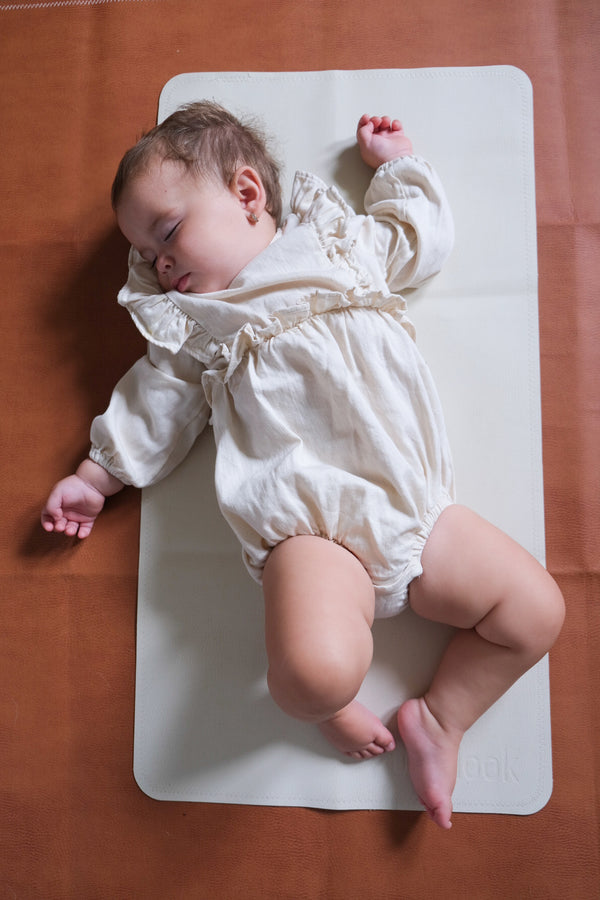 Baby layed on blanc leather mat