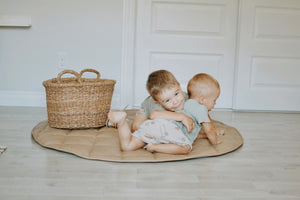 brothers hugging each other sitting on there tan and gray vegan leather floor mat